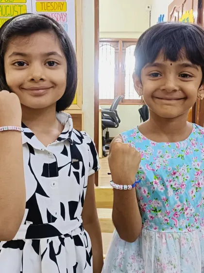 Two friends show off the matching friendship bracelets they made. This activity is not just about crafting, but also about celebrating friendship.