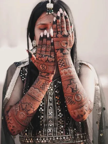 A beautiful photo of the bride with her hands covering her face, showcasing the full extent of her stunning bridal mehndi.