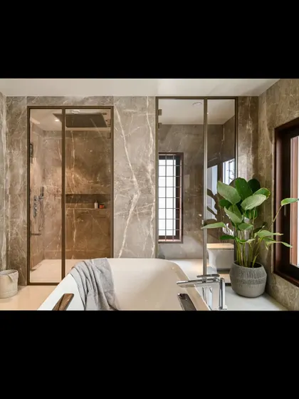 The master bathroom features both a freestanding tub and a spacious walk-in shower, both clad in warm-toned marble. The design provides all the amenities of a luxury spa within the comfort of home.