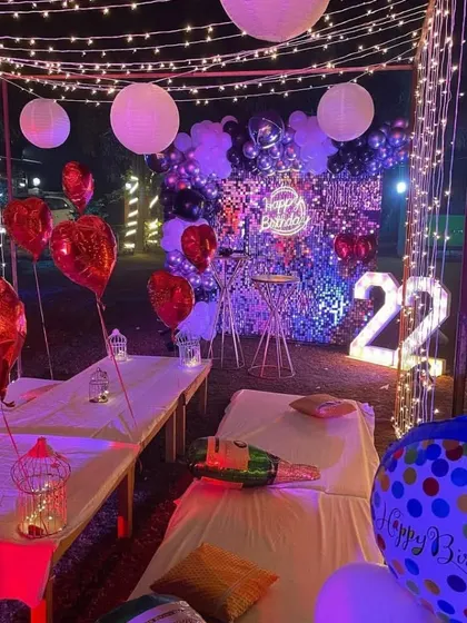 I can create a full party atmosphere outdoors, like this 22nd birthday cabana setup. It includes fairy light curtains, a shimmer wall backdrop, a neon sign, and marquee numbers, along with comfortable seating for guests.
