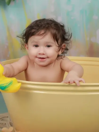 This happy baby plays with a rubber duck during his bath time session. We use classic, fun props to encourage natural smiles and playful interactions.