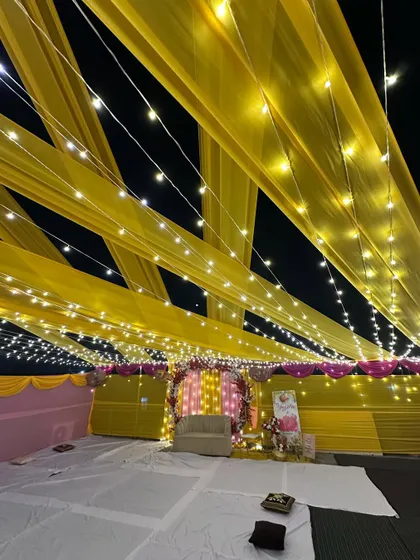 The terrace Haldi setup seen from a distance, showing the scale of the decoration and the beautiful effect of the illuminated canopy against the night sky.