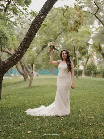 A joyful portrait of the bride, celebrating with her bouquet in a lovely garden setting.