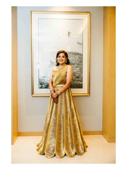 The bride, looking radiant in her golden gown, ready for her Sangeet night. Her elegant outfit is perfect for a night of dancing and celebration.