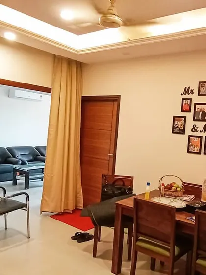 The finished dining and living area. The space is now a warm and inviting home, complete with a wooden dining set, comfortable sofas, and personalized decor like the family photo wall.