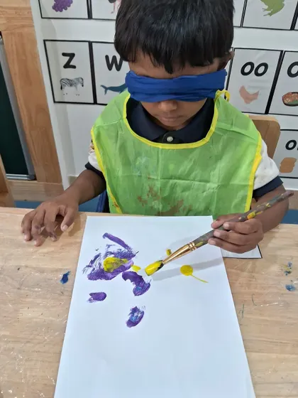 This boy is focused on the feeling of the brush on the paper, exploring art in a completely new way. Blindfold painting helps develop sensory awareness and trust.