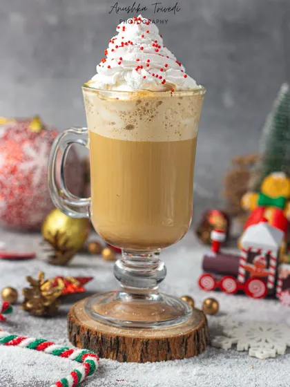 A cozy shot of a Christmas coffee drink topped with whipped cream and sprinkles, set against a festive, snowy background.