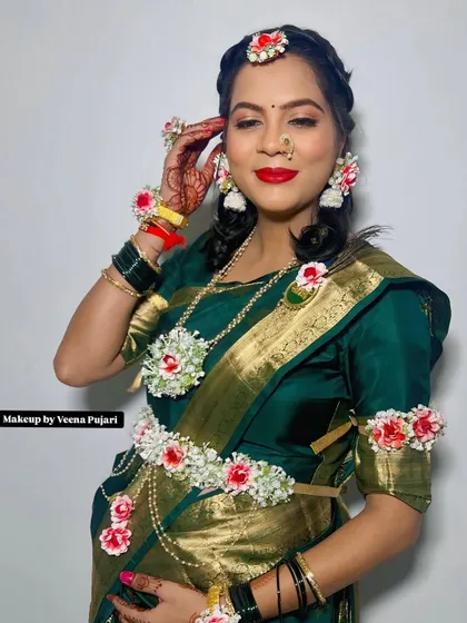 A beautiful mom-to-be adorned with fresh floral jewelry for her baby shower. The red and white flowers add a touch of freshness to her traditional green saree.