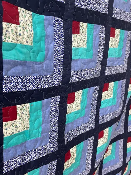 A close-up of a "Quarter Log Cabin" quilt, showing the simple, effective quilting.