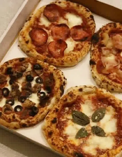 A box of four mini pizzas showcasing the variety I offer. This is a great way to sample different toppings, from a classic Margherita to a meaty pepperoni.