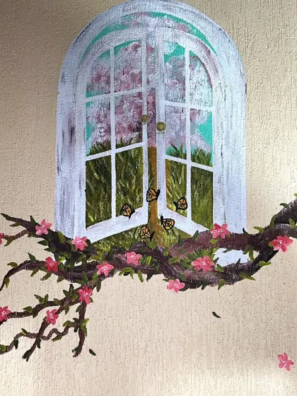 A close-up of the finished window mural, with tiny butterflies fluttering on the branches.