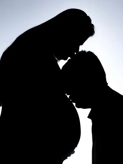 A classic silhouette pose that is always so moving. The father-to-be kissing the baby bump and the mother kissing his forehead creates a beautiful circle of love, captured artistically in the studio.