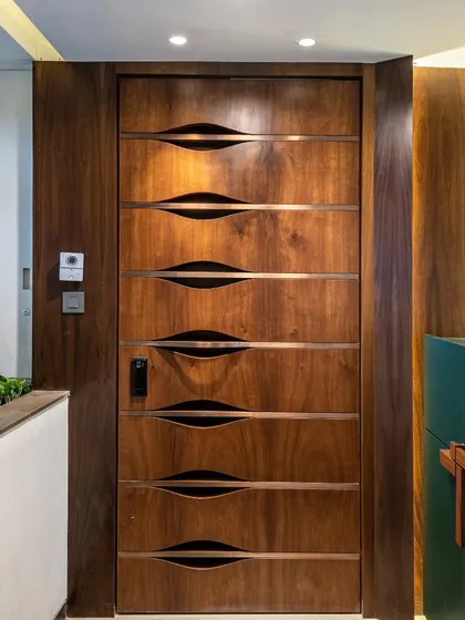The main door of The Filigree House is a work of art in itself. Crafted from rich wood, it features unique, curved inlays that create a sense of rhythm and hint at the detailed craftsmanship found throughout the home.
