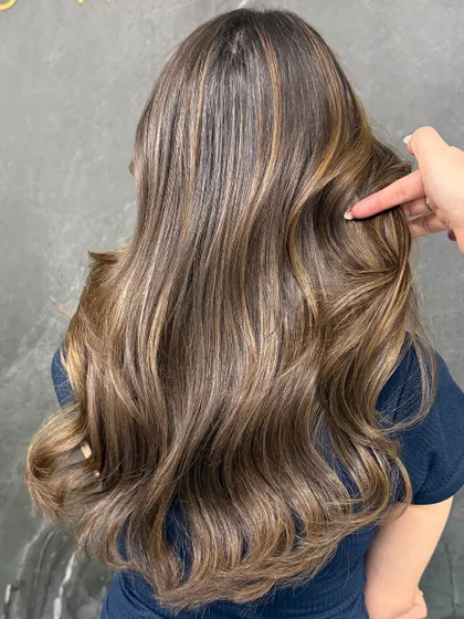 Soft highlights give this client's hair a boost of brightness and dimension, styled into loose waves for an effortless vibe.