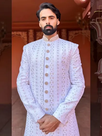 A detailed portrait shot of a groom in our white embroidered sherwani. The mandarin collar and precise fit give it a sharp, regal appearance.