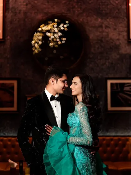 A loving glance between the couple, perfectly framed against a stylish, moody backdrop at their cocktail event.