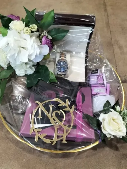 We handle high-value items with the utmost care. This gift platter for the groom features a luxury watch, elegantly packaged with floral accents and a custom laser-cut monogram of the couple's initials for a truly personal touch.