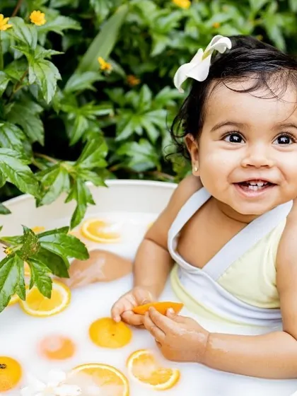 Summer splashes and happy smiles! A milk bath session is a wonderfully fun and unique way to capture your baby's milestones. This little one had a great time playing with oranges in the tub, resulting in some truly adorable and memorable photos.