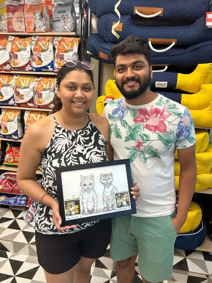 A couple proudly displays a custom caricature of their two cats, a memorable keepsake from our Meow Fest.