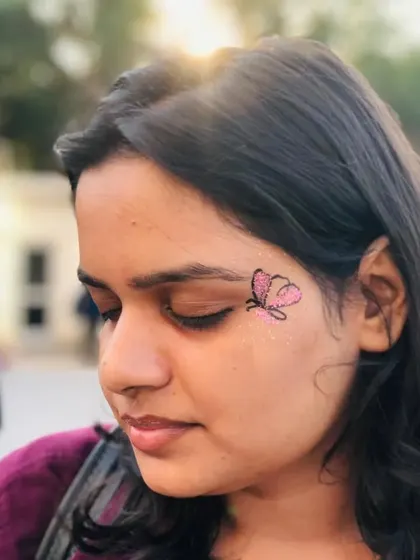 A small, delicate pink butterfly with glitter. This is a perfect first-time face paint design.