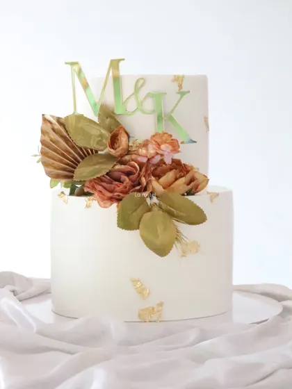 Another view of the vintage-style cake, showing the custom 'M & K' initial topper and the delicate gold leaf accents.