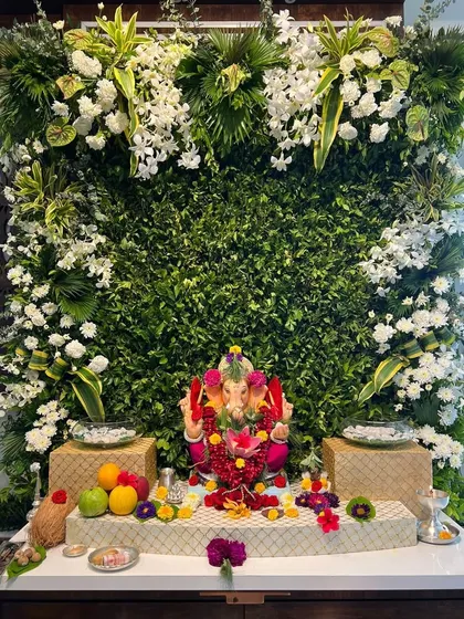 This modern and elegant Ganpati backdrop features a dense wall of fresh greenery, accented with clusters of white orchids and other exotic white flowers. It’s a perfect example of how we blend contemporary style with traditional reverence.
