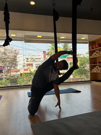 A student uses the hammock to support a deep side stretch, targeting the obliques and inner thighs. Props like the hammock help achieve greater range of motion.