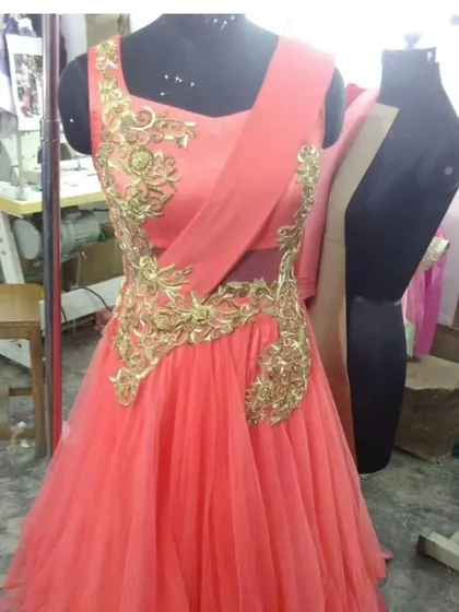 A custom gown taking shape in our workshop. This peach-colored net gown features intricate gold threadwork applique, which we carefully place and stitch by hand to create a flowing, elegant design.