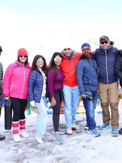 Our group posing for a photo at Khardungla Pass, surrounded by snow and colorful Tibetan prayer flags. This is a moment of shared accomplishment and adventure.