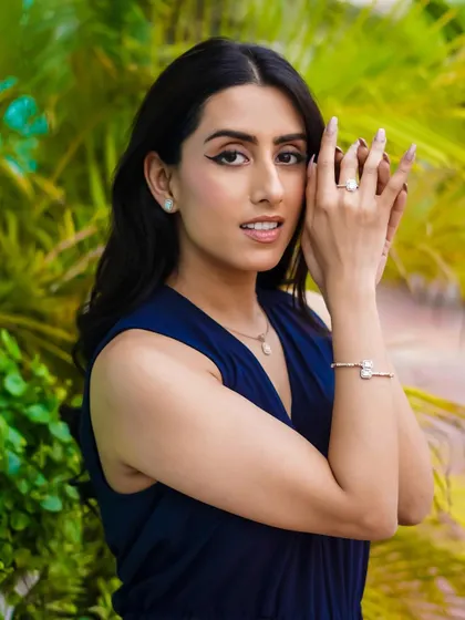 Capturing a moment of connection in this outdoor jewelry shoot. The model's direct gaze and the soft natural light highlight the elegance of the earrings, ring, and bracelet against a vibrant green backdrop.