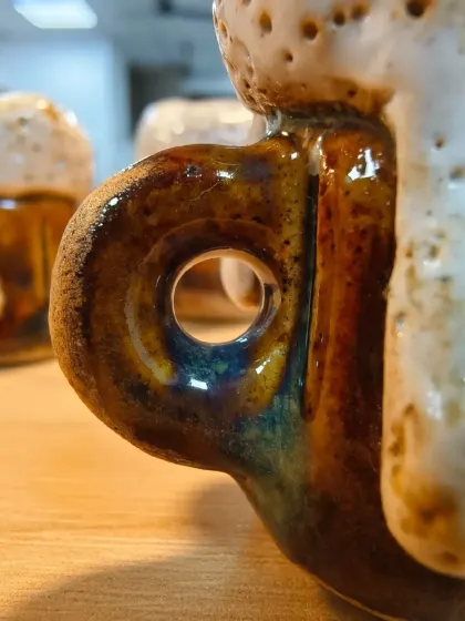 A close-up of the handle on the miniature beer mug, showing the rich, layered colors of the glaze. We teach how to apply glazes to achieve depth and character.