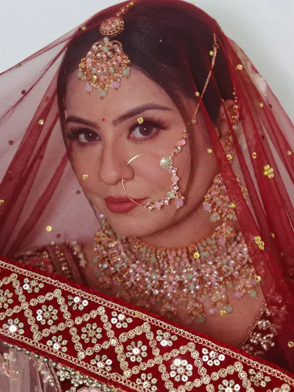 A close-up of the bride looking through her veil. This shot highlights the soft, romantic eye makeup and perfectly matched lip color.