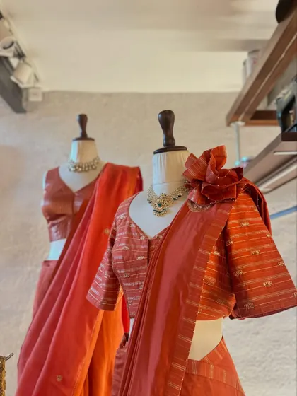 The beauty of a handcrafted blouse. This striped orange blouse with a fabric flower detail adds a touch of playful elegance to the saree, showing how small details can make a big impact.
