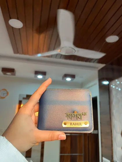 A personalized wallet in a beautiful shade of blue, featuring the name "Rahul" and a "Mahakal" charm. The customization options allow you to create a gift that truly reflects the recipient's personality.