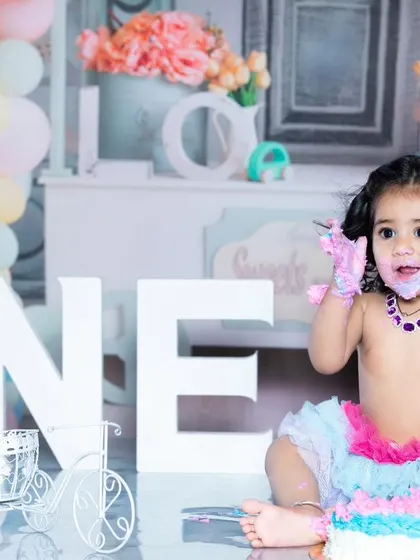 This little girl is celebrating her first birthday in style, with a colorful cake and a tutu.
