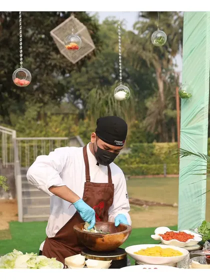 A chef preparing a fresh salad at an outdoor brunch, tossing ingredients in a large wooden bowl.