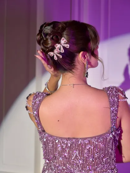 From the side, you can see how the braided bun is complemented by soft, face-framing pieces, creating a look that is both glamorous and flattering.
