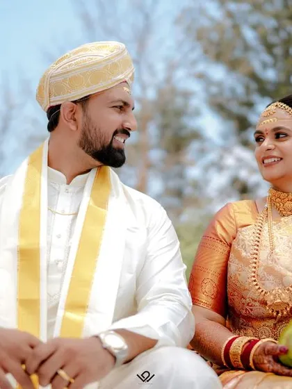 A candid moment between a bride and groom during their South Indian wedding ceremony, sharing a look of love and happiness.