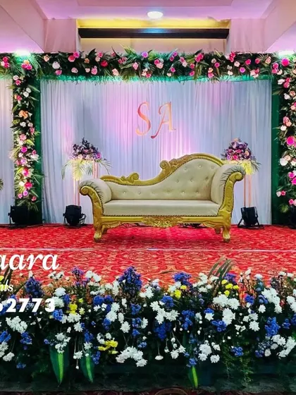 A classic and grand reception stage setup. This design features lush floral borders, elegant white and green drapery, and a custom monogram to personalize the backdrop for the happy couple.