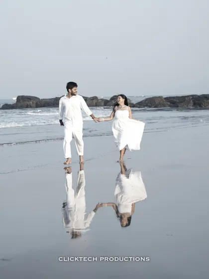 A stunning reflection shot of a couple holding hands and walking on a wet beach in Goa, creating a beautiful, symmetrical image.