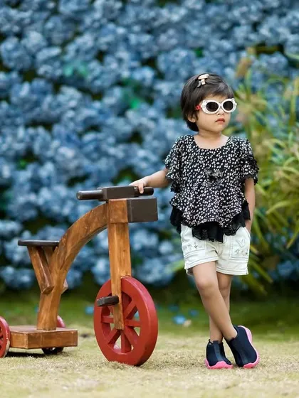 This little fashionista is rocking her sunglasses and posing like a pro next to our wooden bicycle prop in the garden.