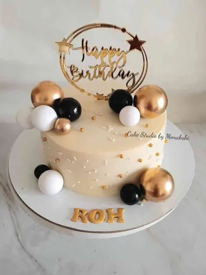 An elegant no-fondant birthday cake in a classic black, white, and gold theme. The balloon-like spheres and custom name detailing make it a sophisticated choice for any celebration.