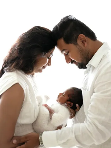 An intimate portrait of new parents with their baby. The forehead-to-forehead pose is a classic way to show connection and love.