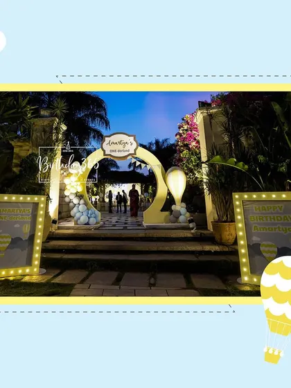 The entrance to Amartya's party at dusk, with lighted marquee signs welcoming the guests to the celebration.