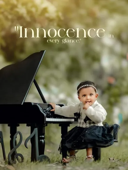 Innocence in every glance. A little girl in a black and white dress gently touches the keys of her mini piano in a green park.