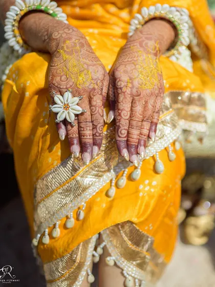 A detailed shot of the bride's hands, adorned with mehendi and beautiful floral jewelry for her Haldi.