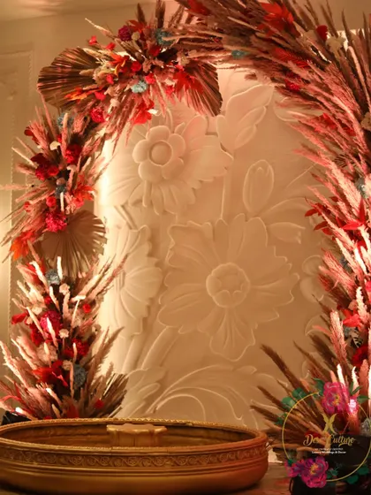 A close-up of the stage from the rustic-themed event, showing the intricate detail of the backdrop and a large brass urli for floating flowers.