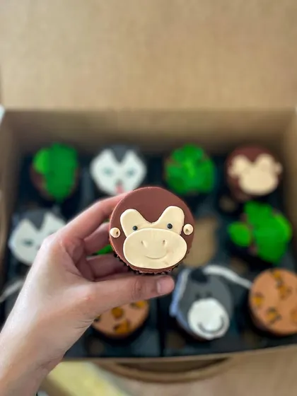 A cute, hand-modelled fondant monkey face on a chocolate cupcake.
