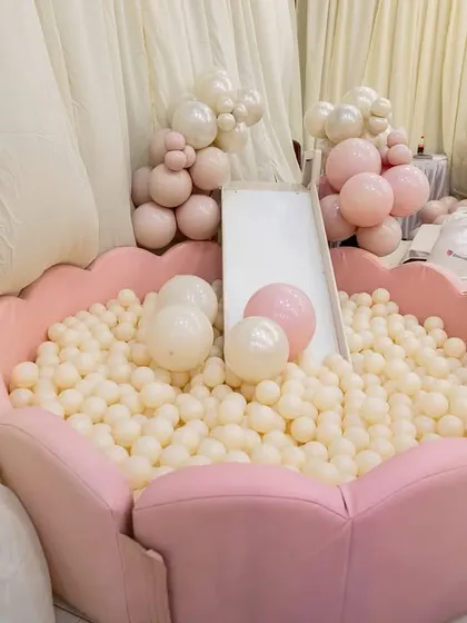 A close-up of the custom-designed, flower-shaped ball pit, filled with white and pink balls to match the party's pastel palette.
