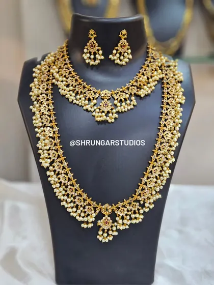 A beautiful bridal combo set with a necklace and matching long haar, both featuring intricate floral motifs and pearl drops.